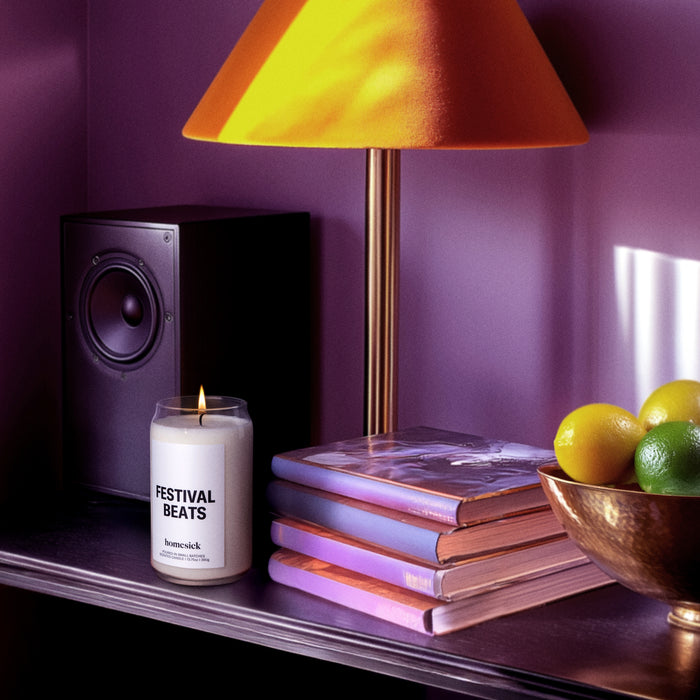 A lit Festival Beats Homesick candle on a well organized desk.