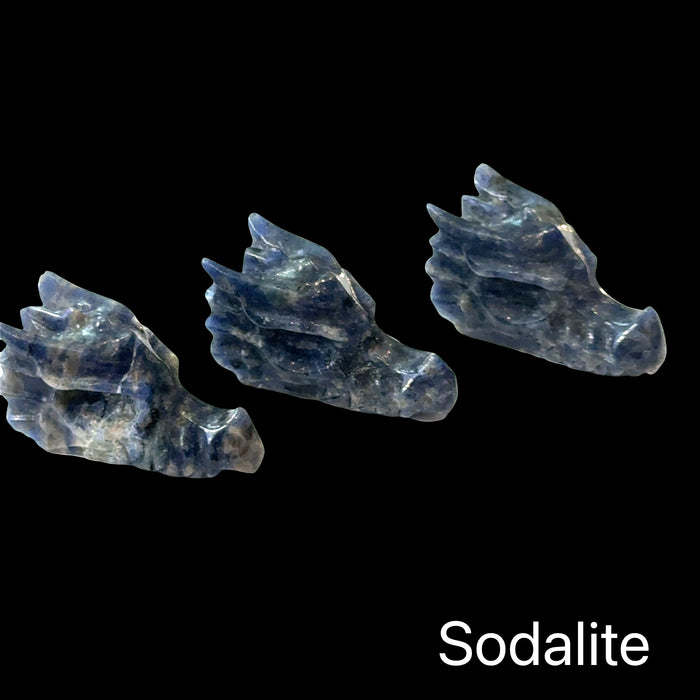 Three sodalite gemstone dragon heads carved in relief on a black background, front-right angle view.