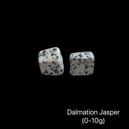 Dalmation Jasper stones with a weight range (0-10g) on a black background, front view.