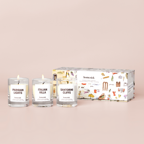 three mini candles labelled "Sanitorini Cliffs", "Italian Villa", and "Parisian Lights" and a box on a cream background