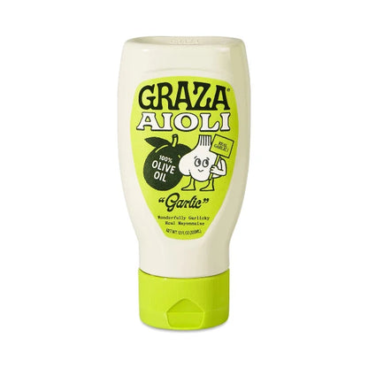 A squeeze bottle of Graza Aioli Garlic Olive Oil dressing on a solid white background. The bottle is off-white with a bright lime green cap and a matching lime green label featuring the brand name and a cartoon garlic character.