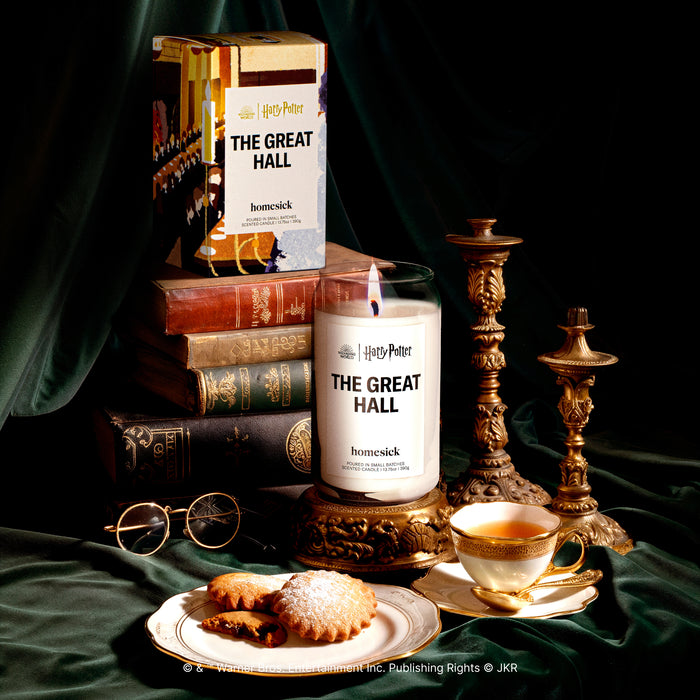 A side by side image of the candle and its packaging. Shot in a decorative environment with several props.