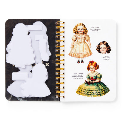 An open Brass Monkey Haunted Dolls Sticker Book displays blank paper cutouts on the left and two wide-eyed, curly-haired illustrated dolls in dresses on the right—perfect for adding your favorite ghostly stickers.