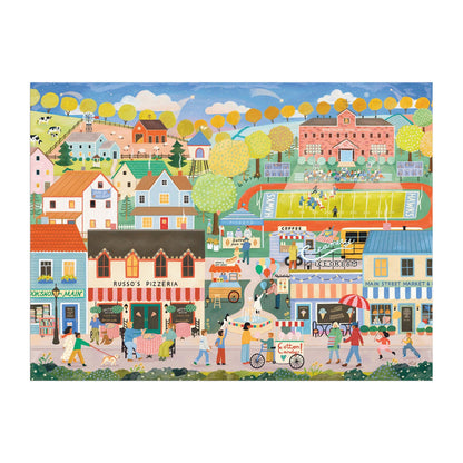 The Hometown Cheer 1000 Piece Puzzle by Elisabeth Dorrian features a vibrant small town scene with shops, restaurants, a pizzeria, people enjoying various activities, yellow-leaved trees, and a football game on a green field.