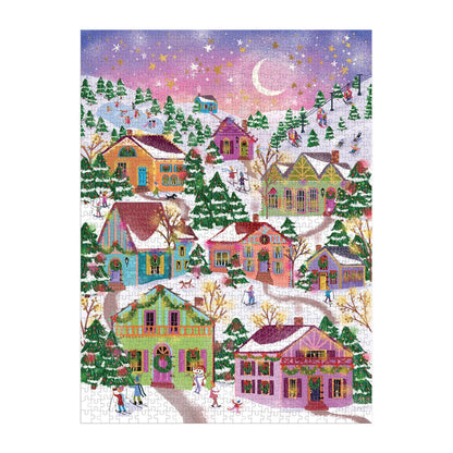 The Joy Laforme Snowcap Village 1000 Piece Foil Puzzle showcases a vibrant winter village scene with festive foil accents, snow-covered houses, pine trees, and people strolling under a crescent moon at sunset.