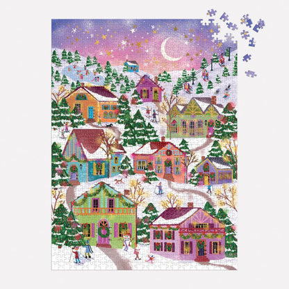 The Joy Laforme Snowcap Village 1000 Piece Foil Puzzle depicts a snowy village with pastel houses, pine trees, people strolling, and a pink-purple sky. A few pieces in the top right are missing from this charming Joy Laforme scene.