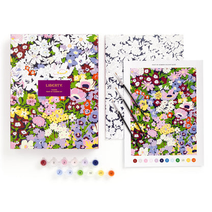 The Liberty London 9 x 12 Paint by Number Kit Thorpe features a colorful pattern reference, a partially painted canvas, two paintbrushes, and twelve numbered paint pots neatly arranged in a row.