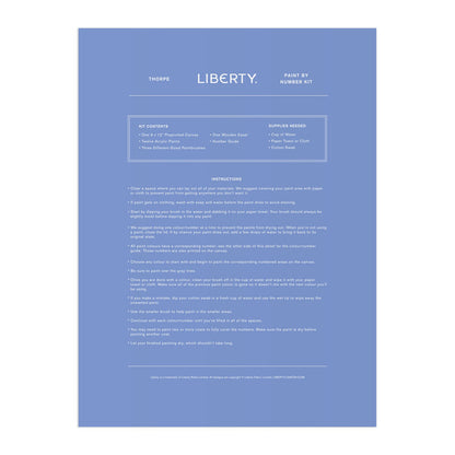 A blue instruction sheet for the Liberty London 9 x 12 Paint by Number Kit Thorpe, featuring white minimalist text listing kit contents, needed supplies, and step-by-step painting instructions, inspired by the Liberty textile archive.