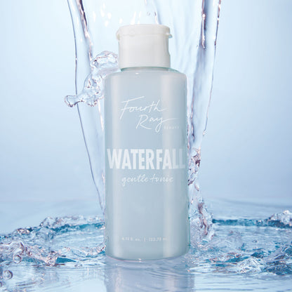 Fourth Ray Beauty Waterfall Gentle Tonic face toner standing upright as water splashes around it, showcasing a pale blue 4.15 fl oz bottle with white flip cap; hydrating ColourPop Face Toner in a fresh waterfall setting.