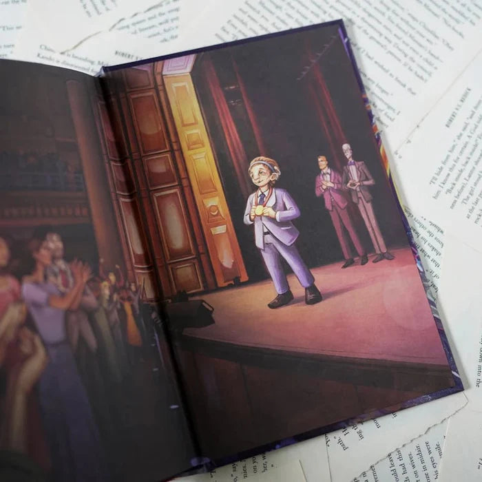 Wonder Annotated Special Edition open book showing interior full-page illustration — a boy in a lavender suit stands on a grand theatre stage flanked by tall wooden doors and red curtains, with an applauding audience and formally dressed figures behind him